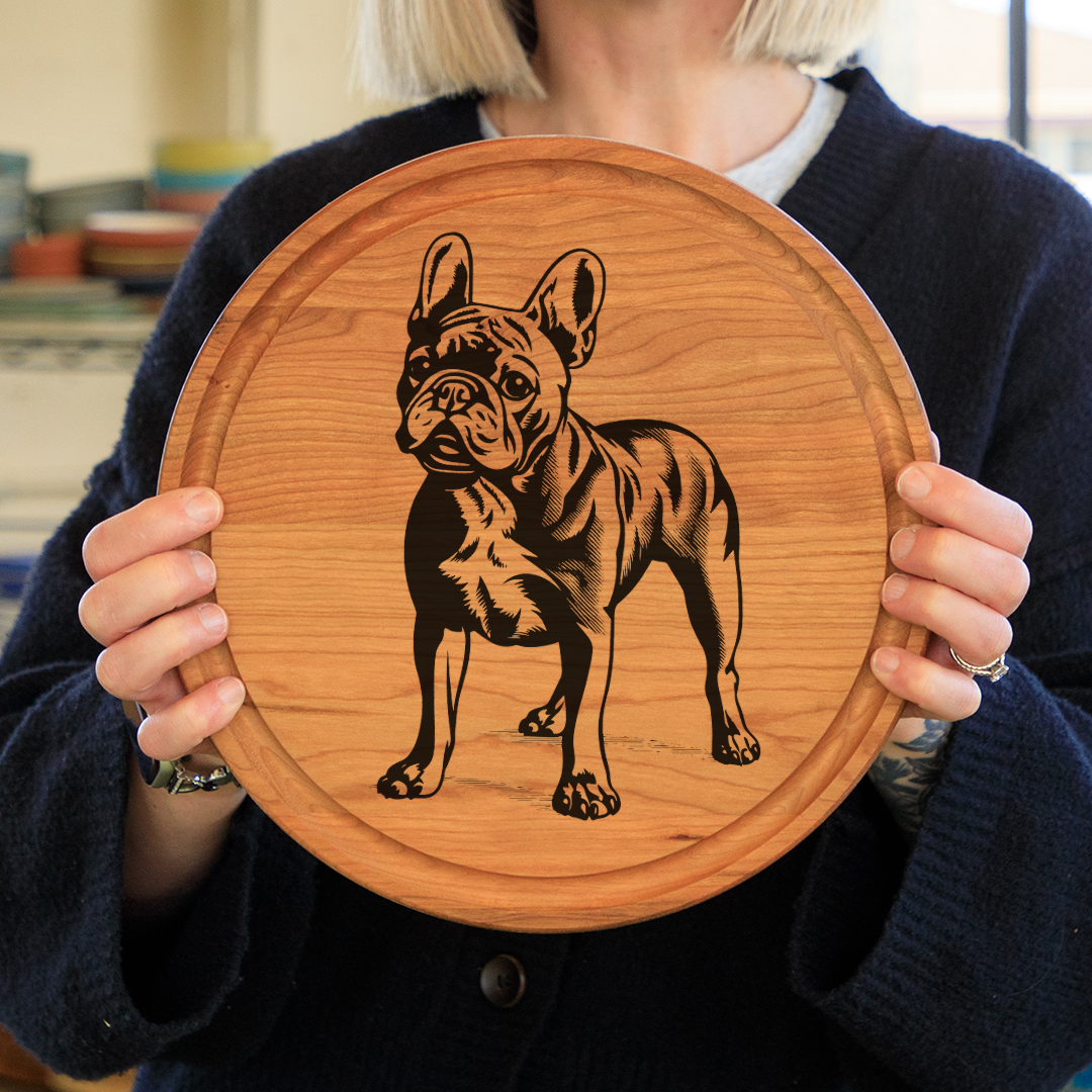 Woman holding a round cherry cutting board with a French Bulldog wood burned into it