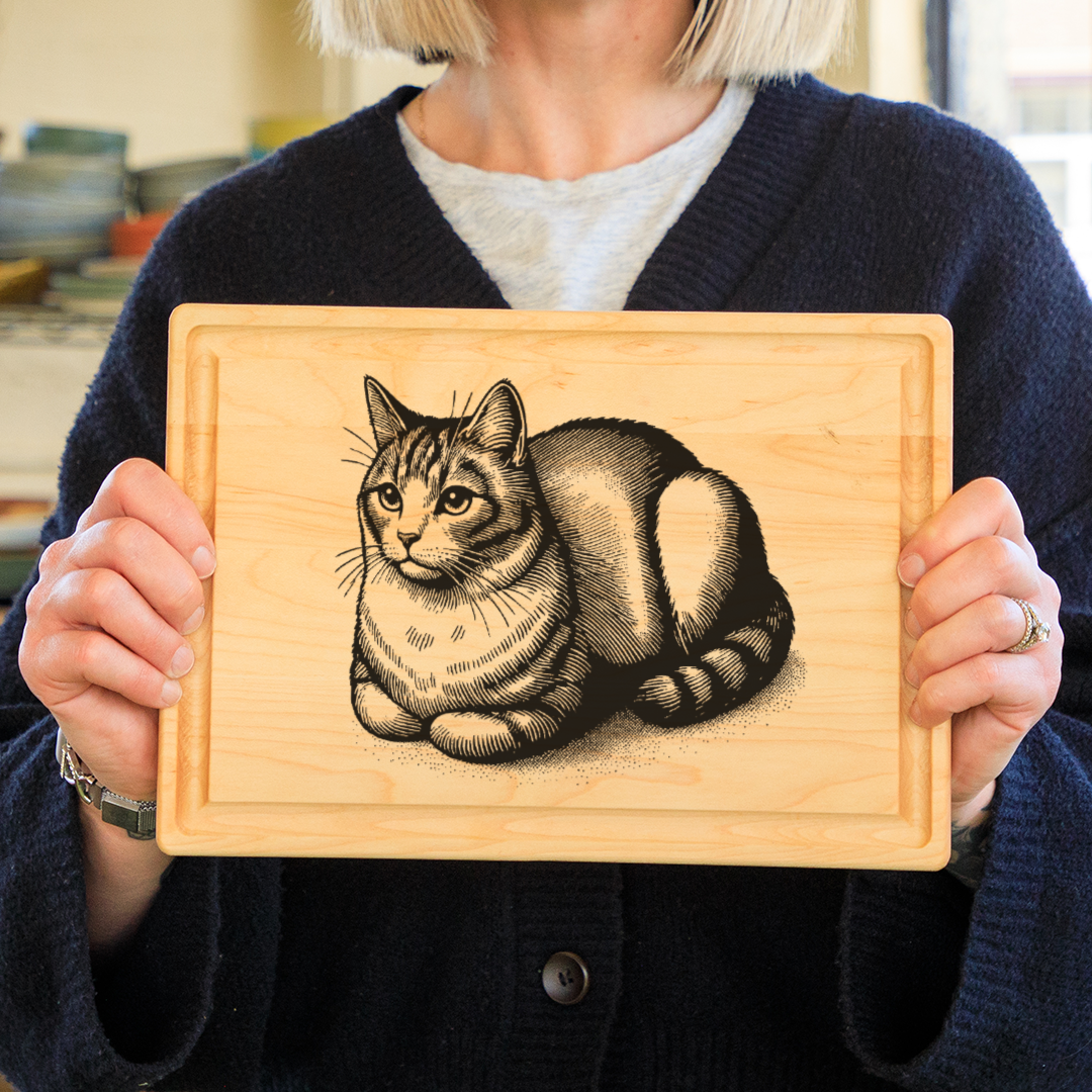 Woman holding a maple rectangular cutting board with a cat in loaf pose wood burned into it